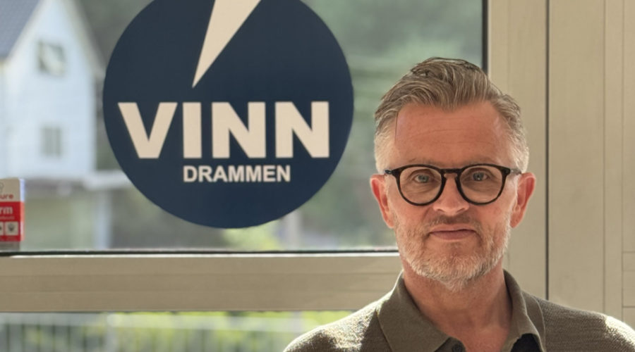 Terje Wårheim står foran vindu med Vinn-logo. Han har briller på seg og hlder opp tommelen