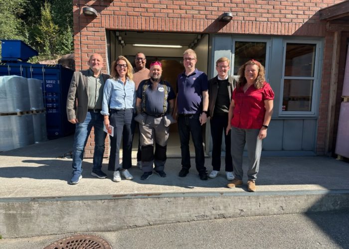 En gruppe mennesker med gjester ra LO og politikken, står samlet foran Vinn lasterampe