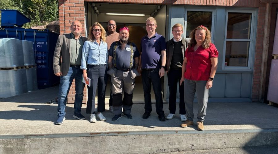 En gruppe mennesker med gjester ra LO og politikken, står samlet foran Vinn lasterampe